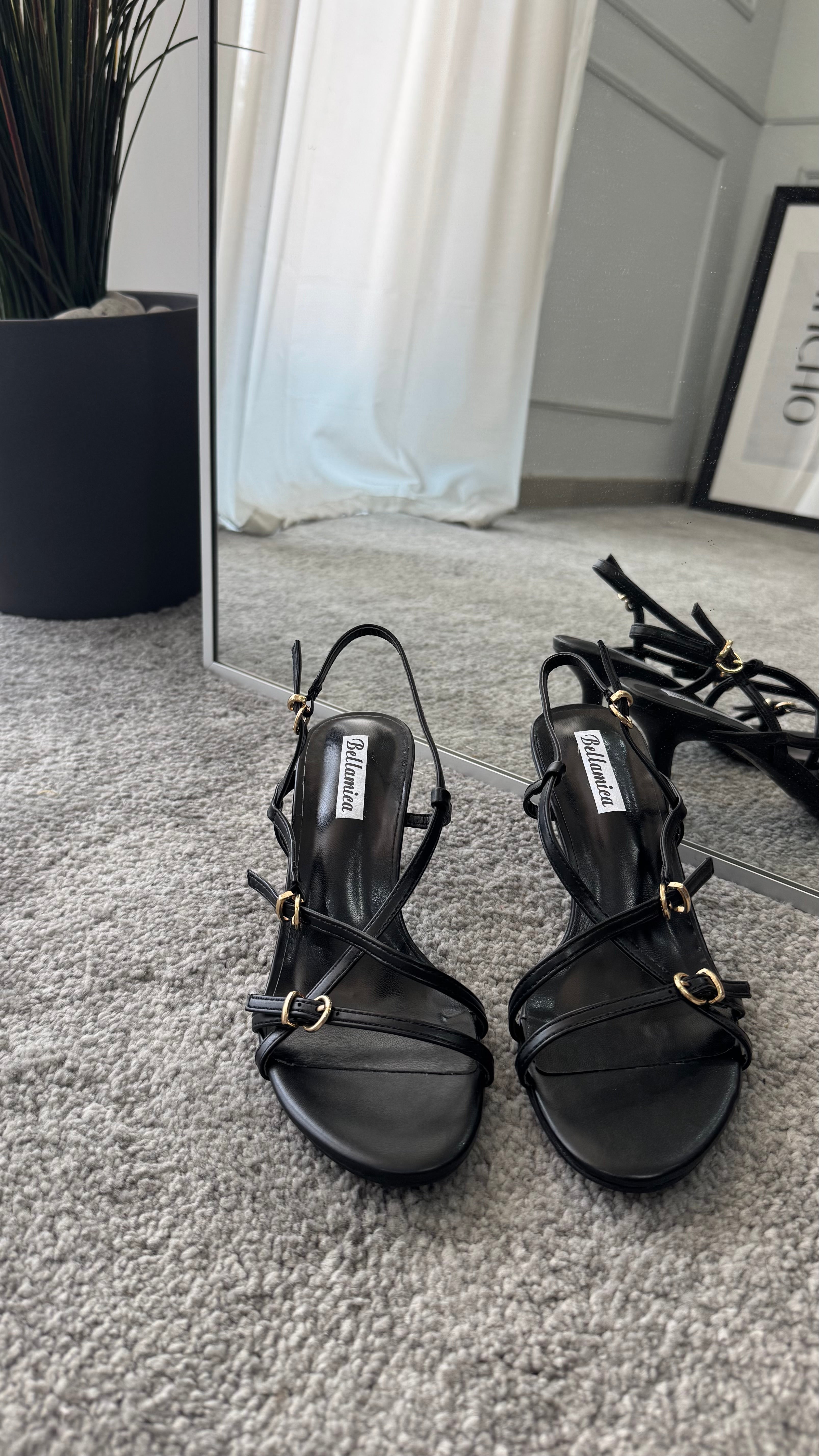 Sandalo black ecopelle sandals with straps and 5cm heel, displayed next to a mirror on a soft carpet.